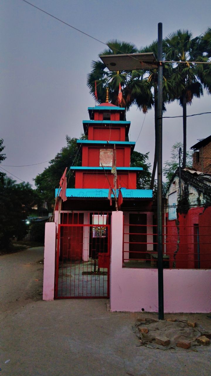A red temple tower framed by palm trees